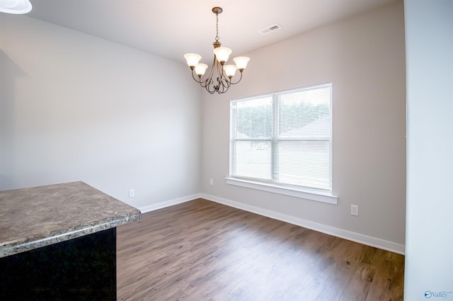 unfurnished dining area with hardwood / wood-style flooring and a chandelier