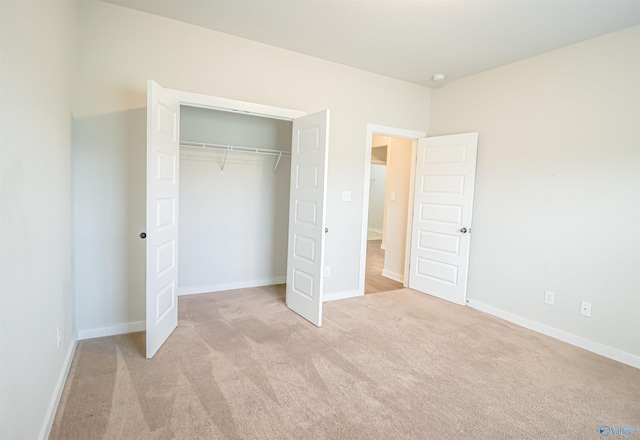 unfurnished bedroom with light colored carpet and a closet