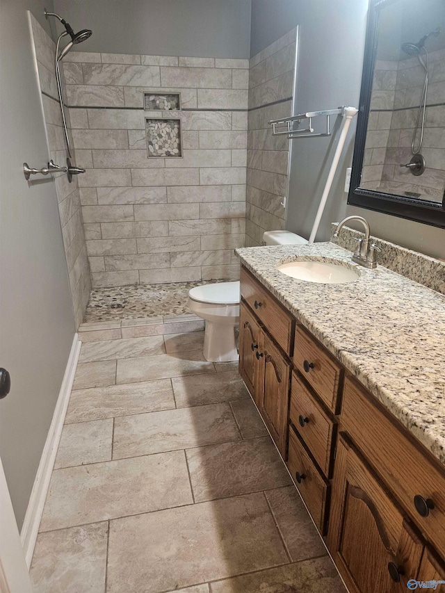 bathroom with tiled shower, vanity, and toilet