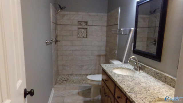 bathroom featuring vanity, toilet, and tiled shower