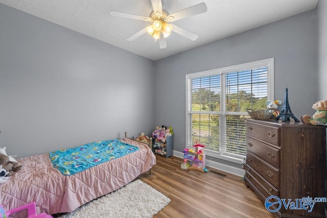 bedroom with light wood-type flooring, a textured ceiling, and ceiling fan