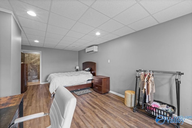 bedroom with hardwood / wood-style flooring, a paneled ceiling, and a wall mounted AC