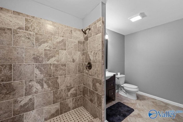 bathroom with vanity, toilet, and a tile shower