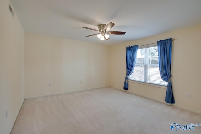 spare room featuring a ceiling fan, light colored carpet, visible vents, and baseboards