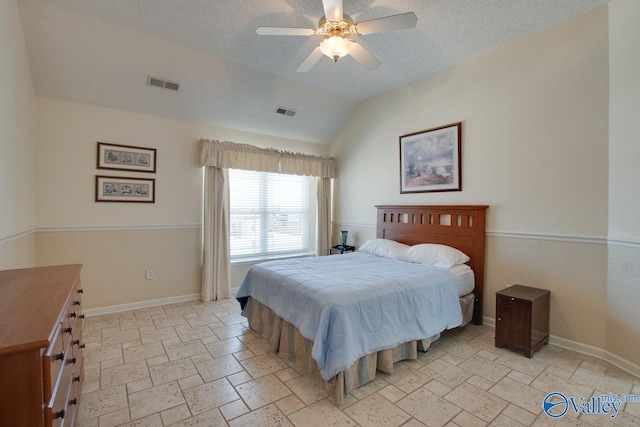 bedroom with lofted ceiling, a textured ceiling, stone tile floors, visible vents, and baseboards