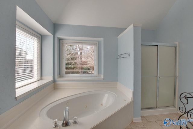 bathroom featuring a stall shower, tile patterned flooring, vaulted ceiling, and a jetted tub