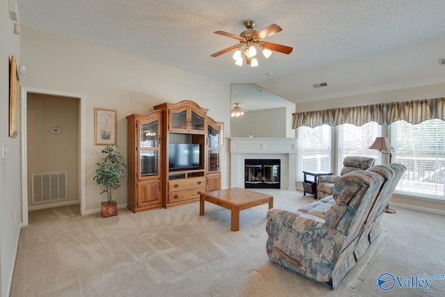 living area featuring light colored carpet, visible vents, vaulted ceiling, and ceiling fan