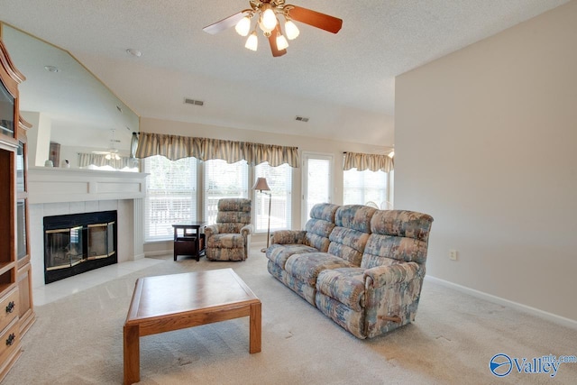 carpeted living area featuring a ceiling fan, baseboards, a textured ceiling, and a tiled fireplace