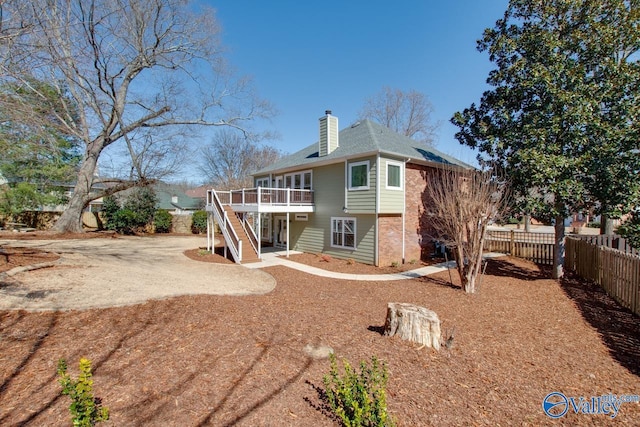 back of property with fence private yard, a chimney, stairway, and a wooden deck