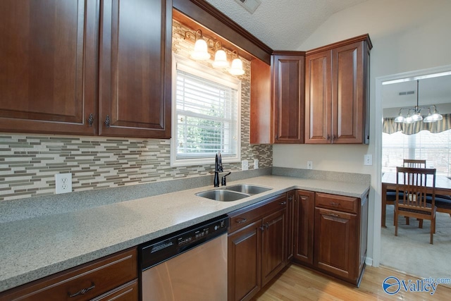 kitchen featuring light countertops, backsplash, stainless steel dishwasher, light wood-style floors, and a sink