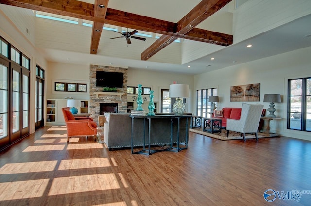 living room featuring beamed ceiling, a towering ceiling, and wood finished floors