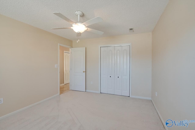 unfurnished bedroom with light carpet, baseboards, visible vents, a textured ceiling, and a closet