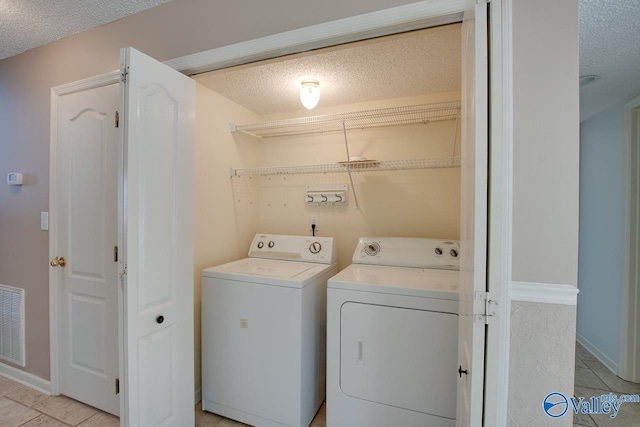 clothes washing area featuring laundry area, visible vents, washing machine and clothes dryer, a textured ceiling, and light tile patterned flooring