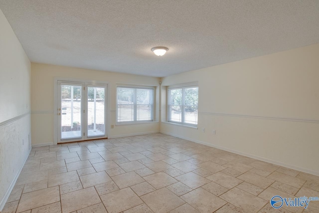 unfurnished room with stone finish floor, a textured ceiling, and baseboards