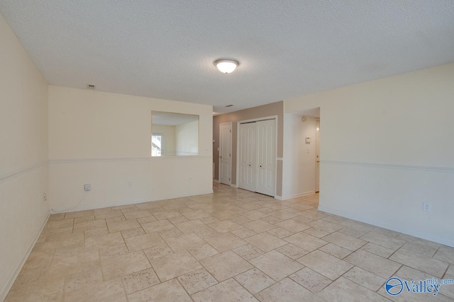 empty room with baseboards and a textured ceiling