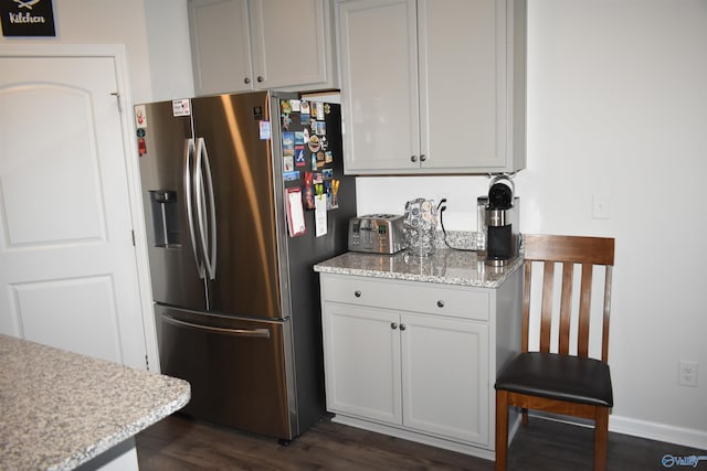 kitchen featuring dark wood-style floors, stainless steel fridge, baseboards, and light stone countertops