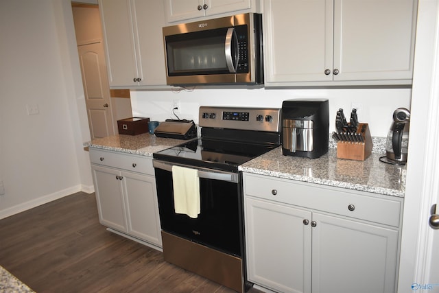 kitchen with baseboards, appliances with stainless steel finishes, dark wood-type flooring, and light stone countertops