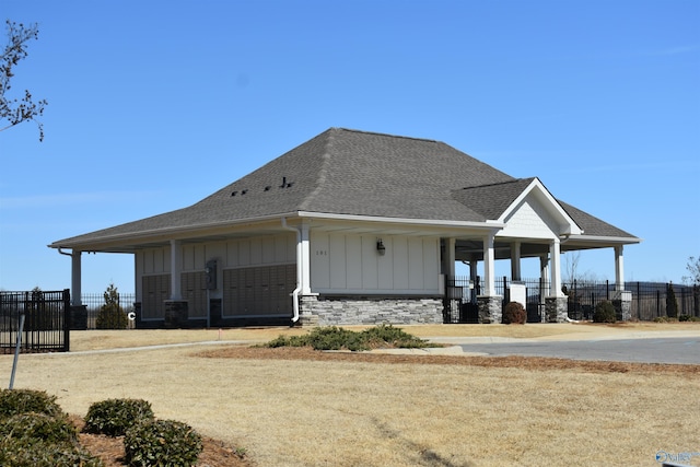 exterior space featuring stone siding, fence, board and batten siding, and roof with shingles