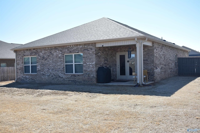 back of property with roof with shingles, fence, and brick siding