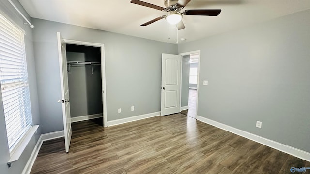 unfurnished bedroom with hardwood / wood-style flooring, multiple windows, ceiling fan, and a closet