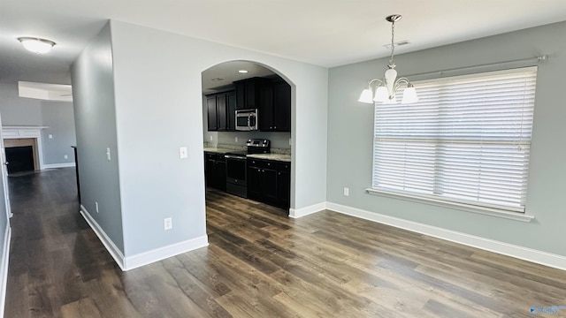 kitchen with stainless steel appliances, hanging light fixtures, dark hardwood / wood-style floors, and an inviting chandelier