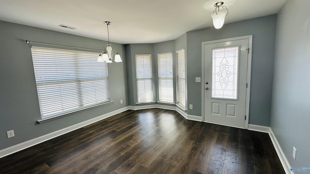 foyer entrance with dark wood-type flooring and a notable chandelier