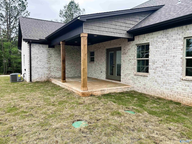 15685 Huntsville Brownsferry Rd, Athens, AL 35611 - back of property with a patio area, roof with shingles, central air condition unit, a lawn, and brick siding