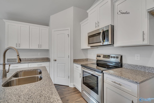 kitchen featuring stainless steel appliances, white cabinetry, light stone countertops, and sink