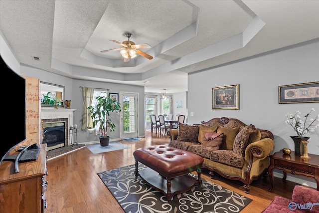 194 Bonaire Dr, Huntsville, AL 35811 - living room featuring a raised ceiling, a ceiling fan, a textured ceiling, a brick fireplace, and wood finished floors