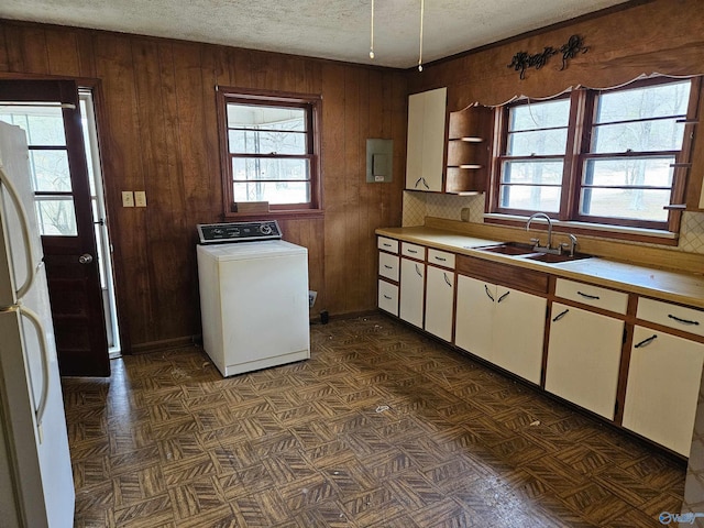 kitchen featuring plenty of natural light, washer / clothes dryer, freestanding refrigerator, light countertops, and a sink