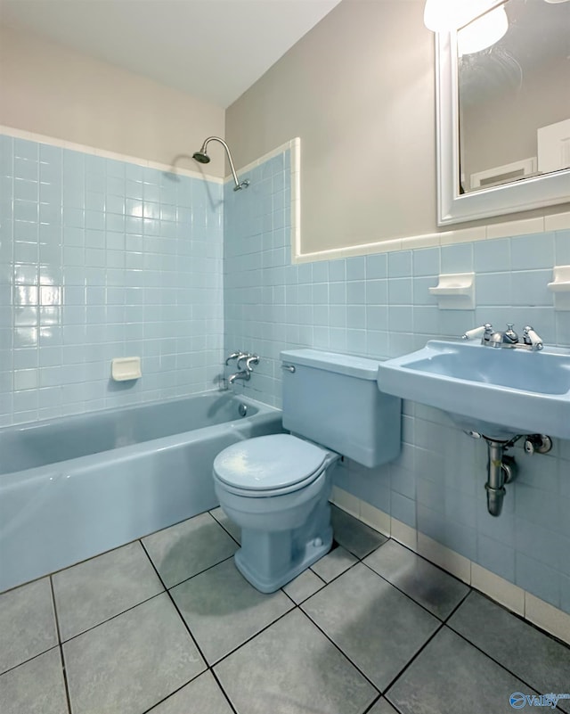 bathroom featuring tile patterned floors, tiled shower / bath, tile walls, and toilet