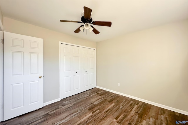 unfurnished bedroom featuring ceiling fan, a closet, and dark wood-type flooring