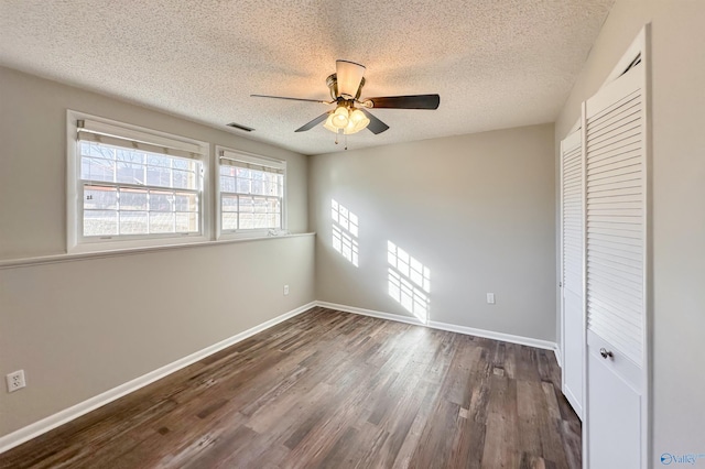 unfurnished bedroom with a textured ceiling, a closet, ceiling fan, and dark wood-type flooring