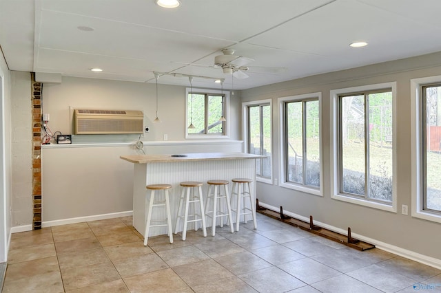 kitchen featuring a kitchen breakfast bar, ceiling fan, light tile patterned floors, and a wall mounted AC