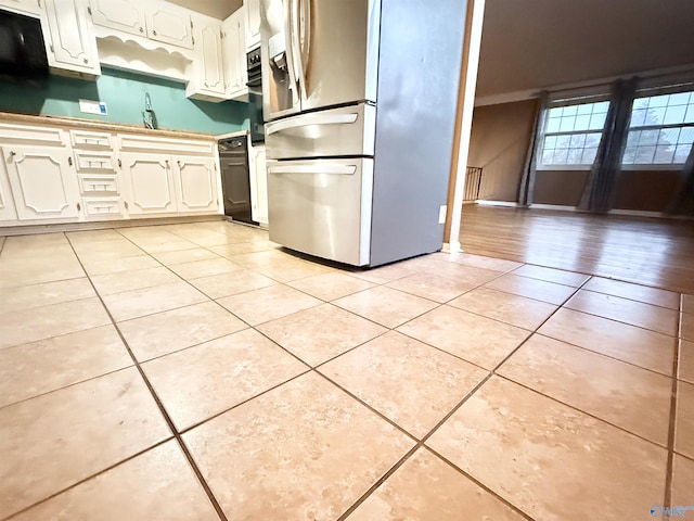 kitchen with white cabinets, stainless steel fridge, sink, and light tile patterned floors