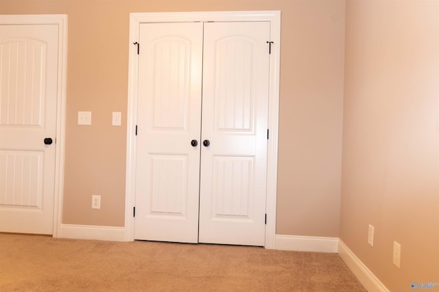 unfurnished bedroom featuring a closet and light carpet