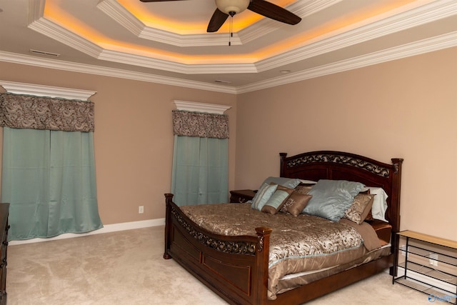 carpeted bedroom featuring ceiling fan, ornamental molding, and a tray ceiling