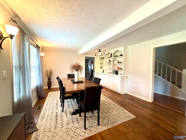 dining area with built in features, dark wood-type flooring, a textured ceiling, and beam ceiling