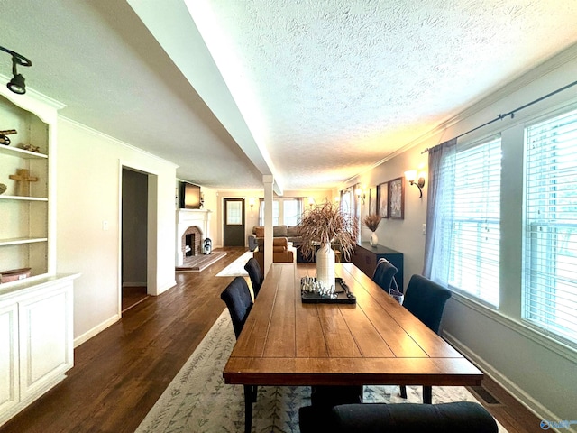 dining room with built in shelves, dark hardwood / wood-style flooring, ornamental molding, and a textured ceiling