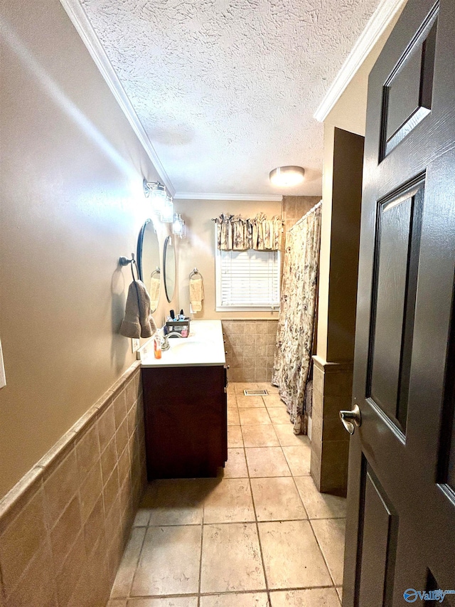 bathroom with tile patterned floors, crown molding, vanity, and a textured ceiling