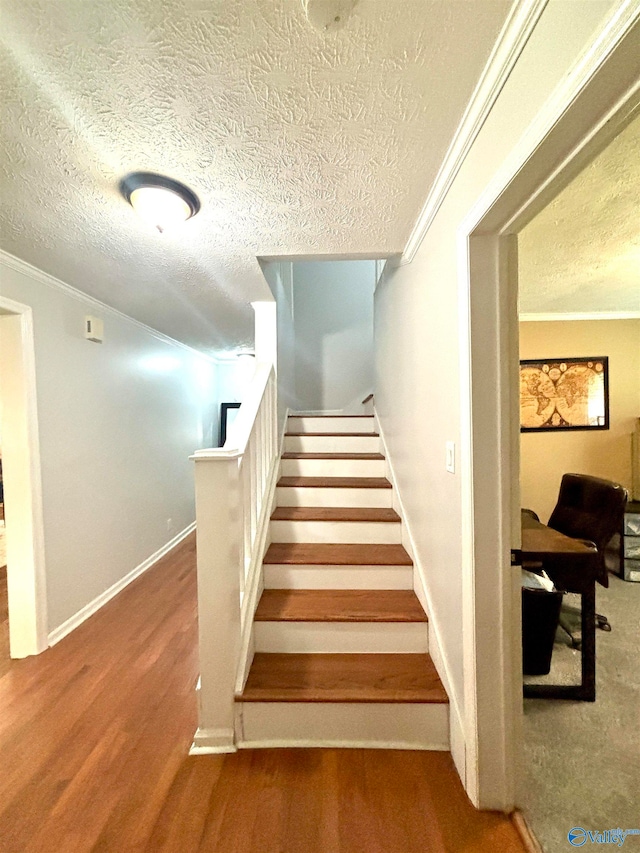 stairs with a textured ceiling, hardwood / wood-style flooring, and crown molding