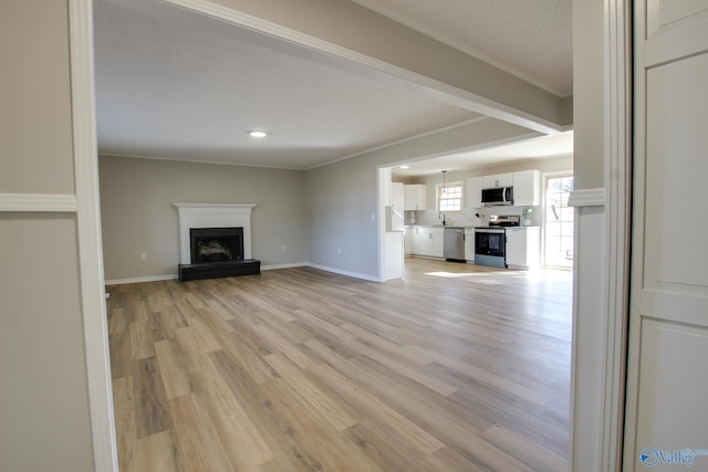 unfurnished living room with a brick fireplace, sink, and light wood-type flooring