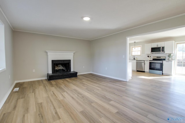 unfurnished living room with a brick fireplace, crown molding, light hardwood / wood-style floors, and sink