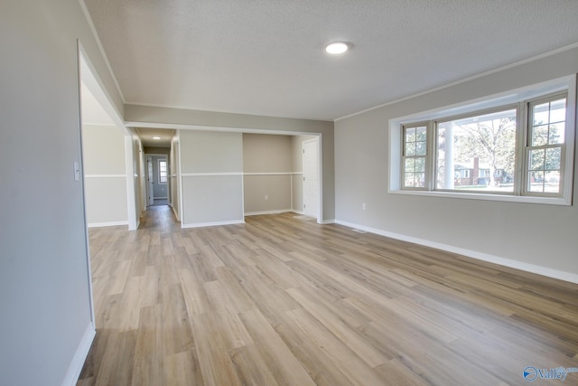 unfurnished living room featuring crown molding, light hardwood / wood-style floors, and a textured ceiling