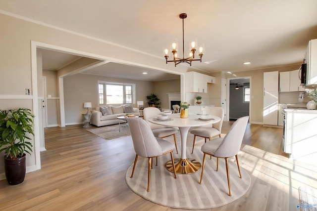 dining area with crown molding, a chandelier, and light wood-type flooring