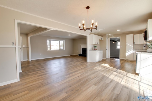 unfurnished living room with a notable chandelier, light hardwood / wood-style flooring, and ornamental molding