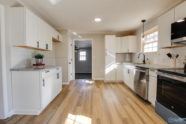 kitchen featuring hanging light fixtures, appliances with stainless steel finishes, white cabinets, and light wood-type flooring