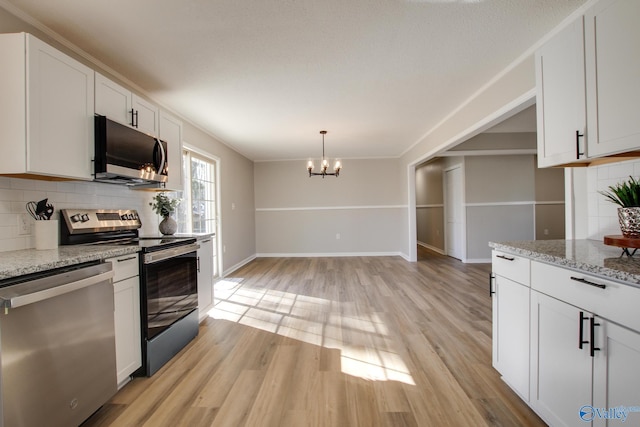 kitchen featuring appliances with stainless steel finishes, light stone counters, light hardwood / wood-style floors, white cabinets, and decorative backsplash