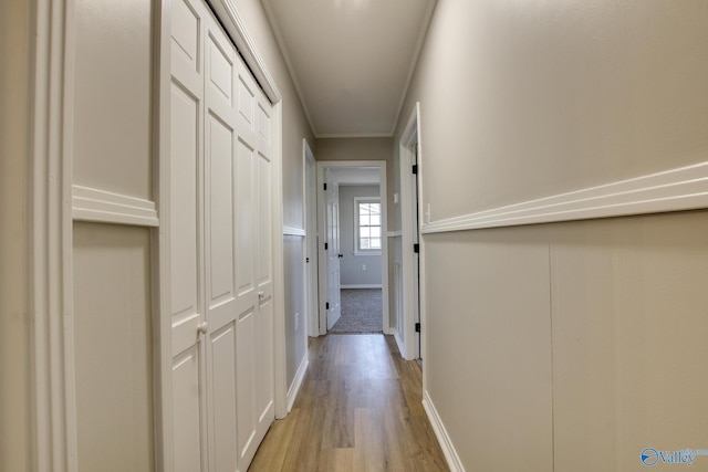 hall with ornamental molding and light hardwood / wood-style flooring