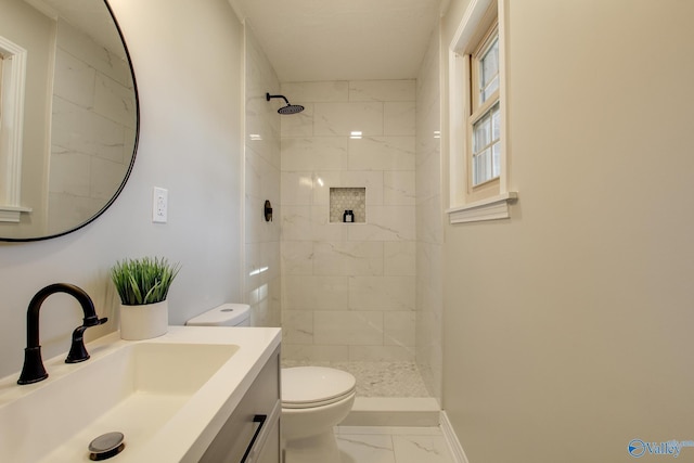 bathroom featuring vanity, toilet, and a tile shower